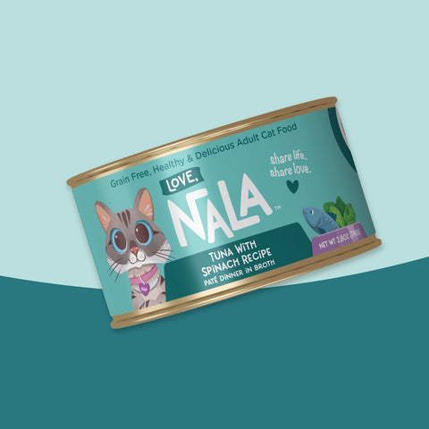 A single can of NALA Love brand adult cat food, tuna with spinach recipe, shown at an angle against a split light blue and dark teal background.